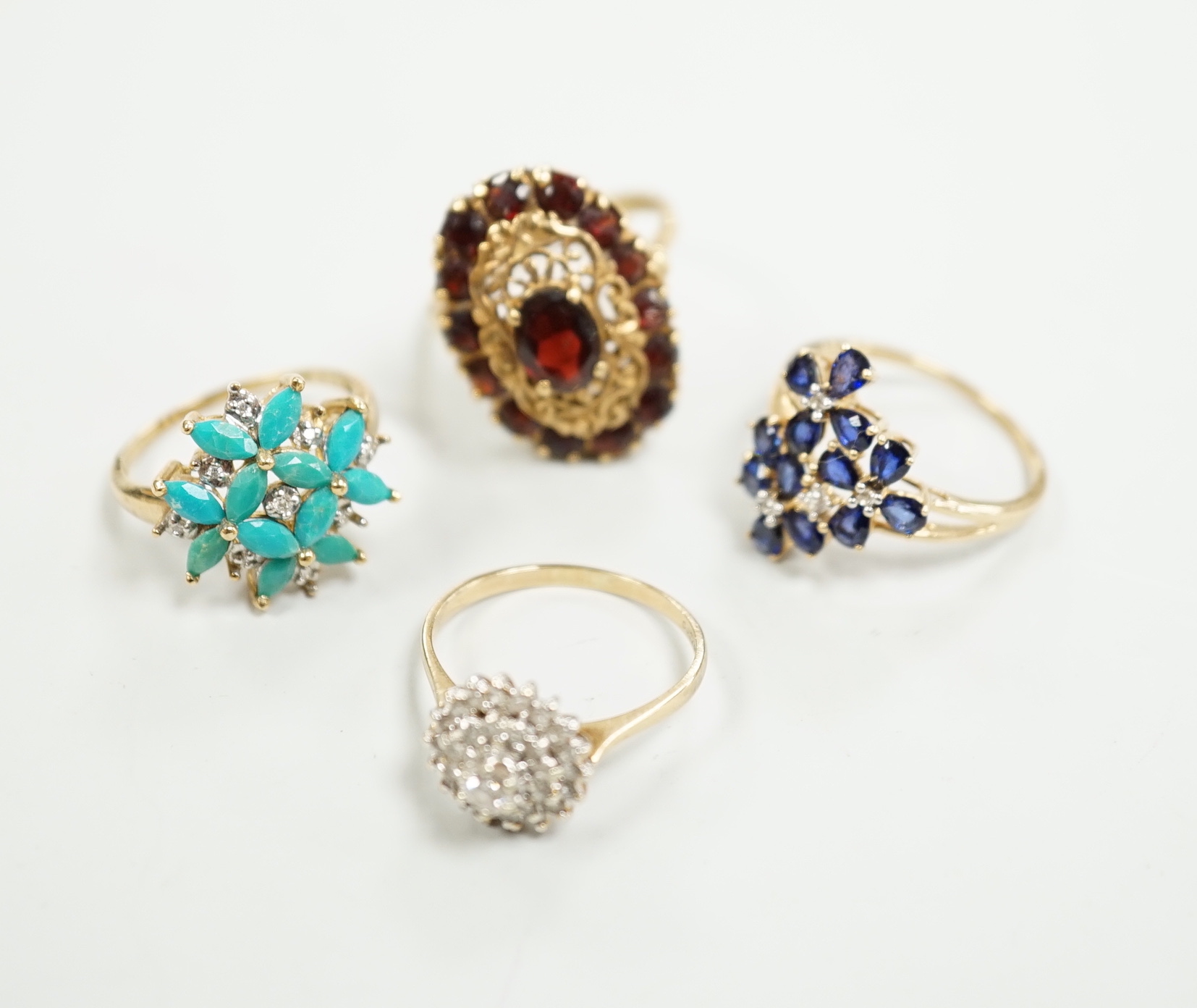 Four assorted modern 9ct gold and gem set dress rings including diamond cluster and garnet cluster, gross weight 13.6 grams.